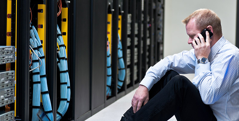 businessman with laptop and a smartphone in network server room
